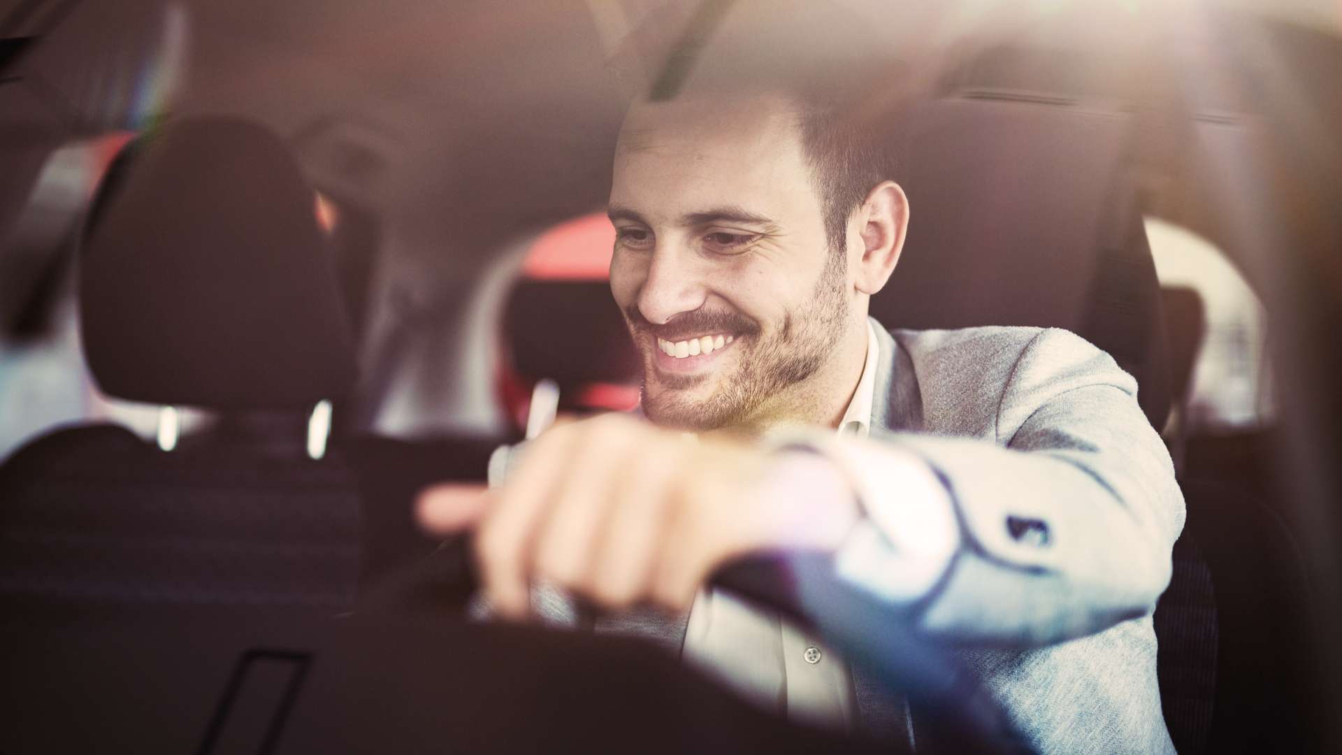 Attractive happy young man driving car and smiling