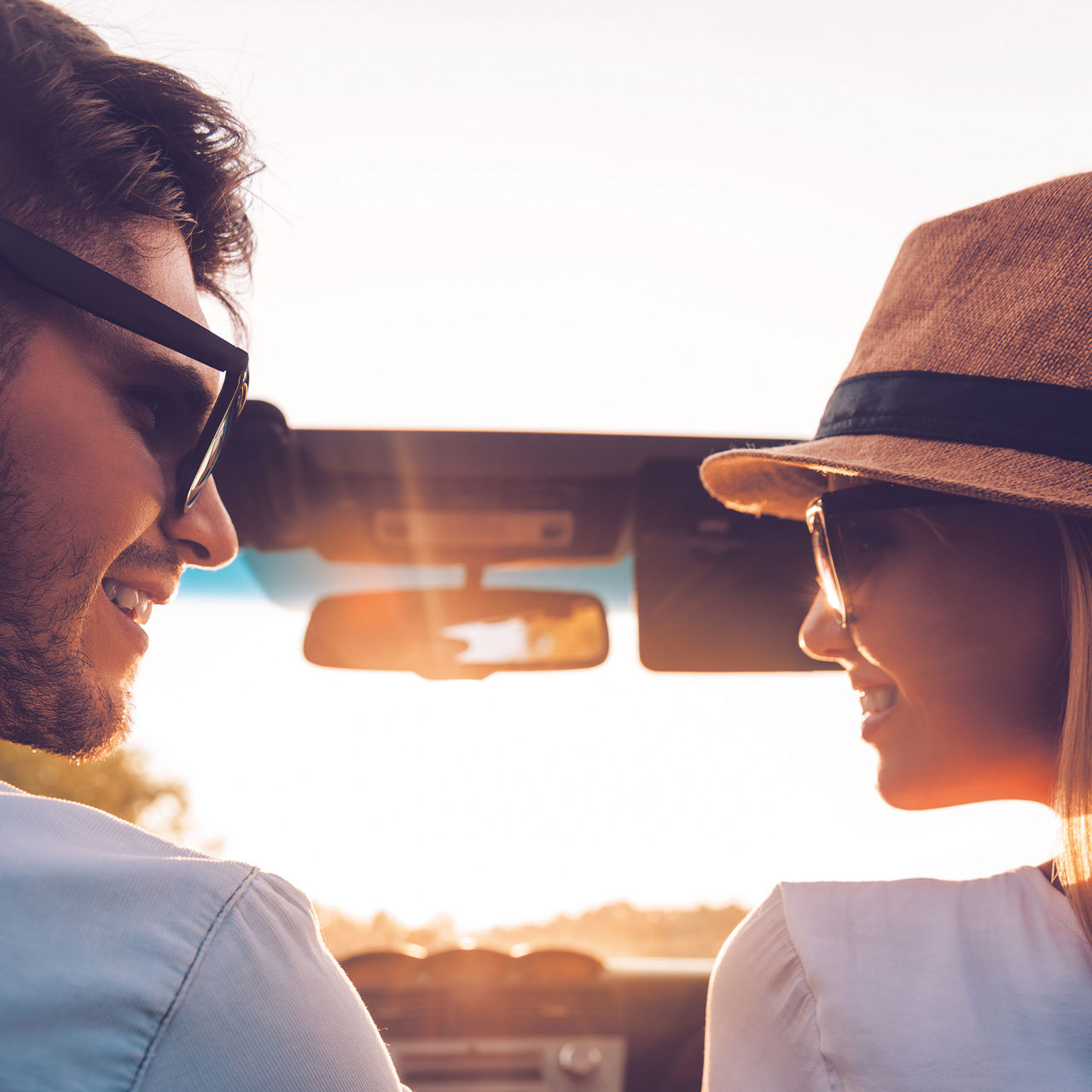 Enjoying every minute together. Rear view of happy young couple looking at each other while sitting inside of their convertible 