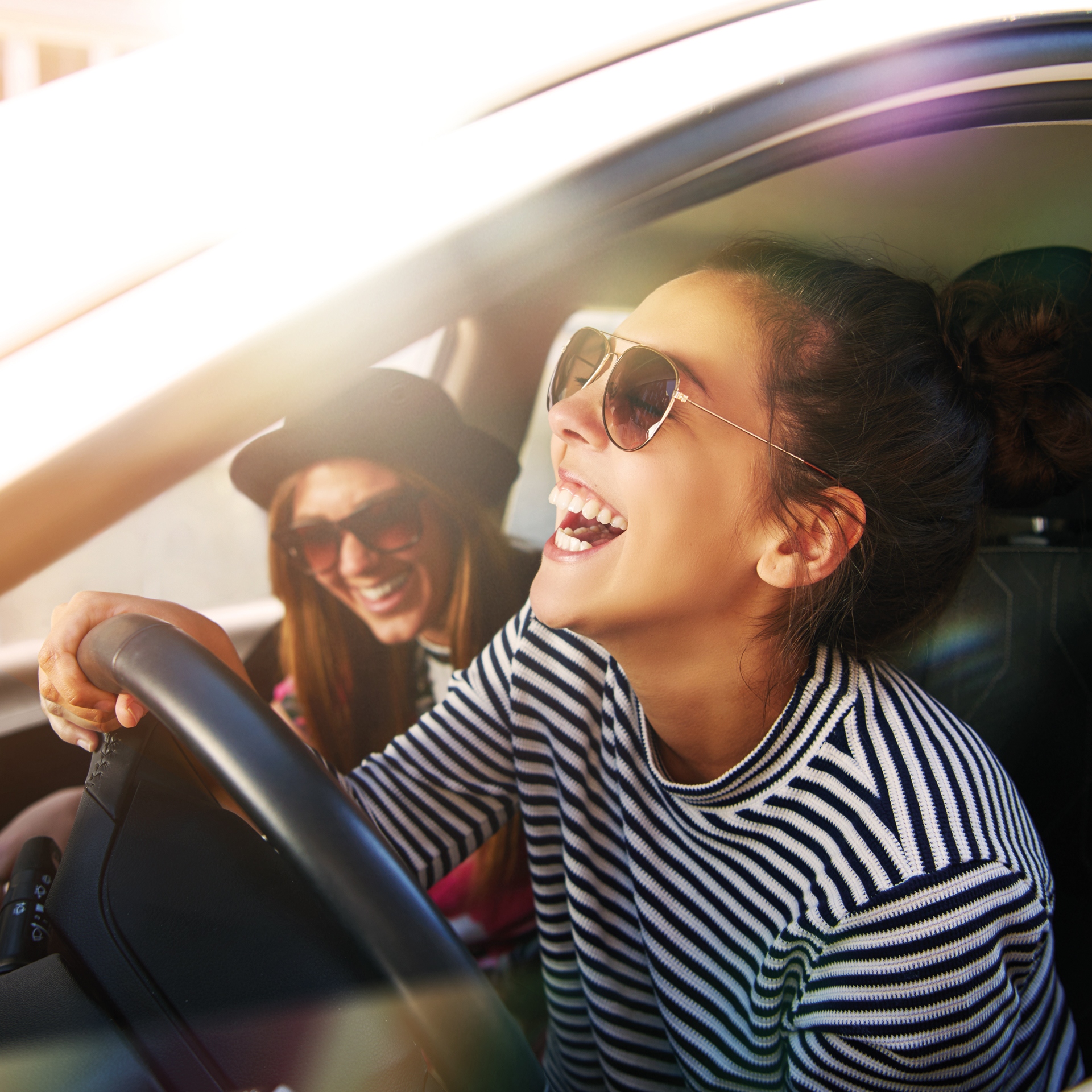 Carefree young friends driving together in a car laughing