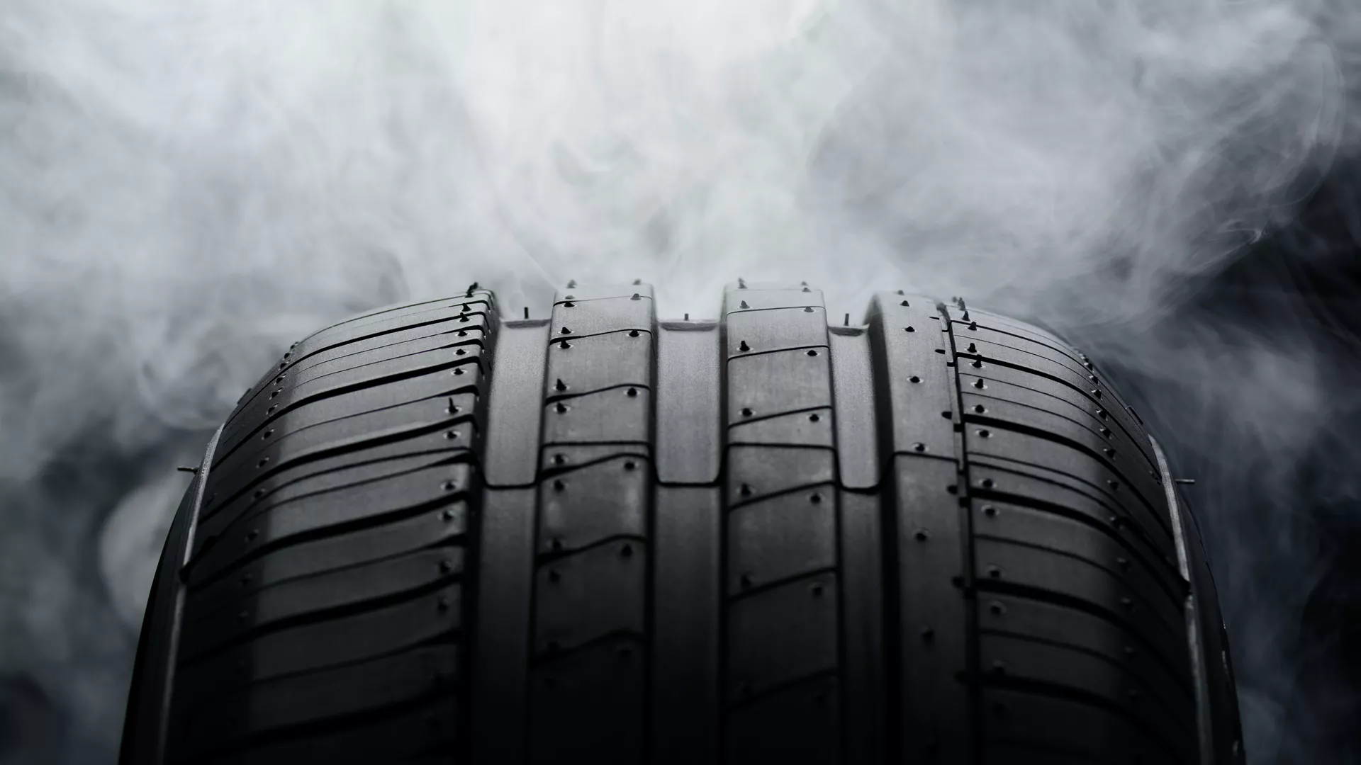 Car tire and smoke on black background image teaser.png