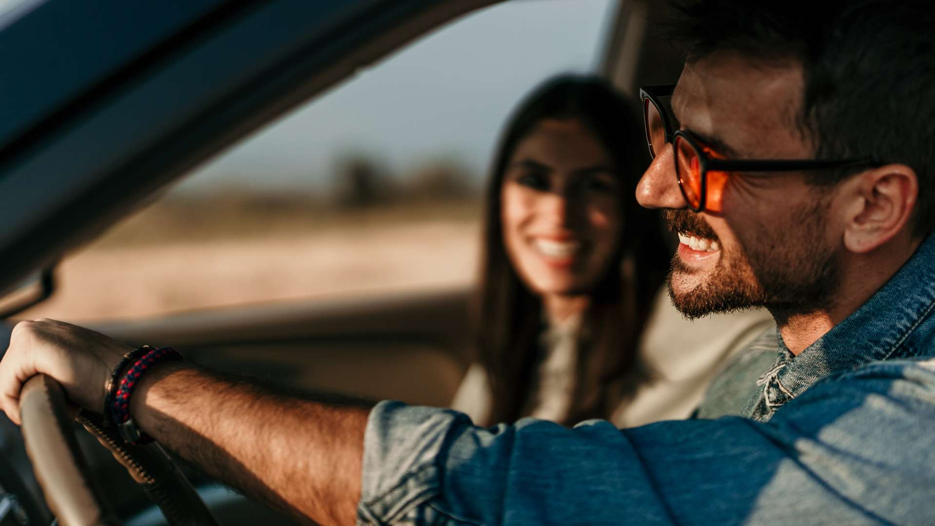 Mann fährt Auto, während seine Beifahrerin ihn anlächet