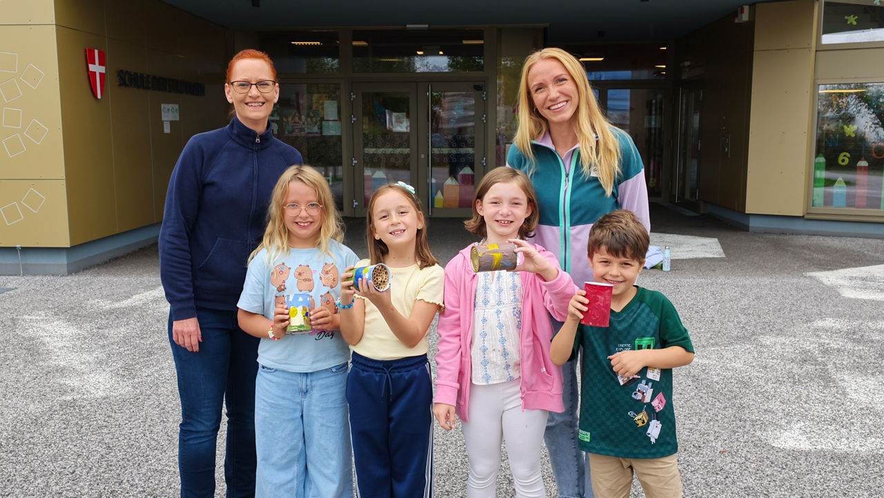 Schulkinder zeigen selbst gebaute Wildbienen-Nisthilfen beim Naturschutzprojekt von BestDrive by Continental und Artenglück an der Volksschule Carlbergergasse in Wien.