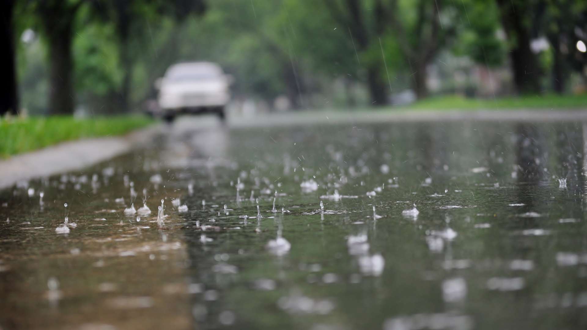 Water flowing along the street curb during heavy rain. Close up of splashing raindrops and air bubbles.