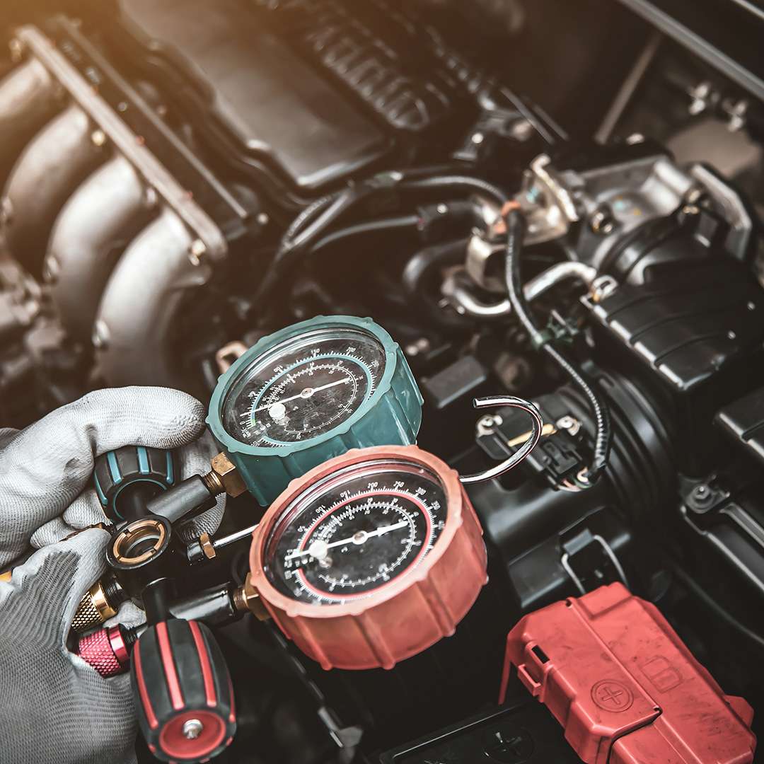 Close up hand of auto mechanic using measuring manifold gauge check the refrigerant and filling car air conditioner for fix and checking for repair service support maintenance and car insurance.