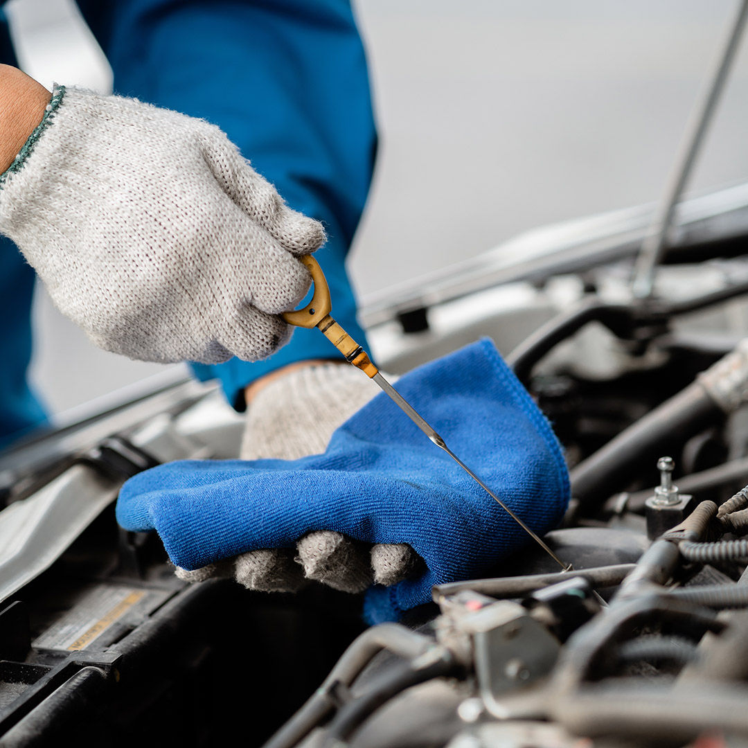 Close-up, a car mechanic checking the oil in a car's engine. Technician inspecting and maintaining the engine of a car or vehicle. Female car mechanic checking car engine