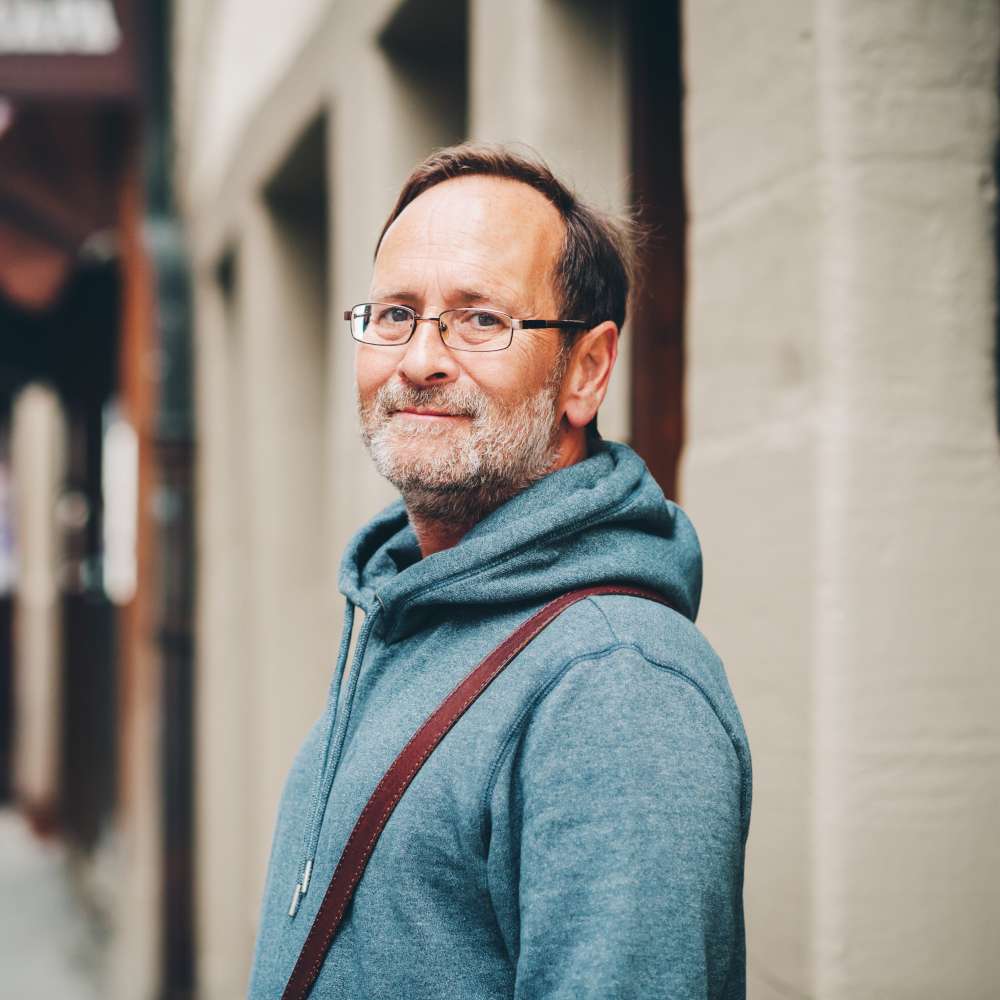 Outdoor portrait of 50 year old man wearing blue hoody and eyeglasses